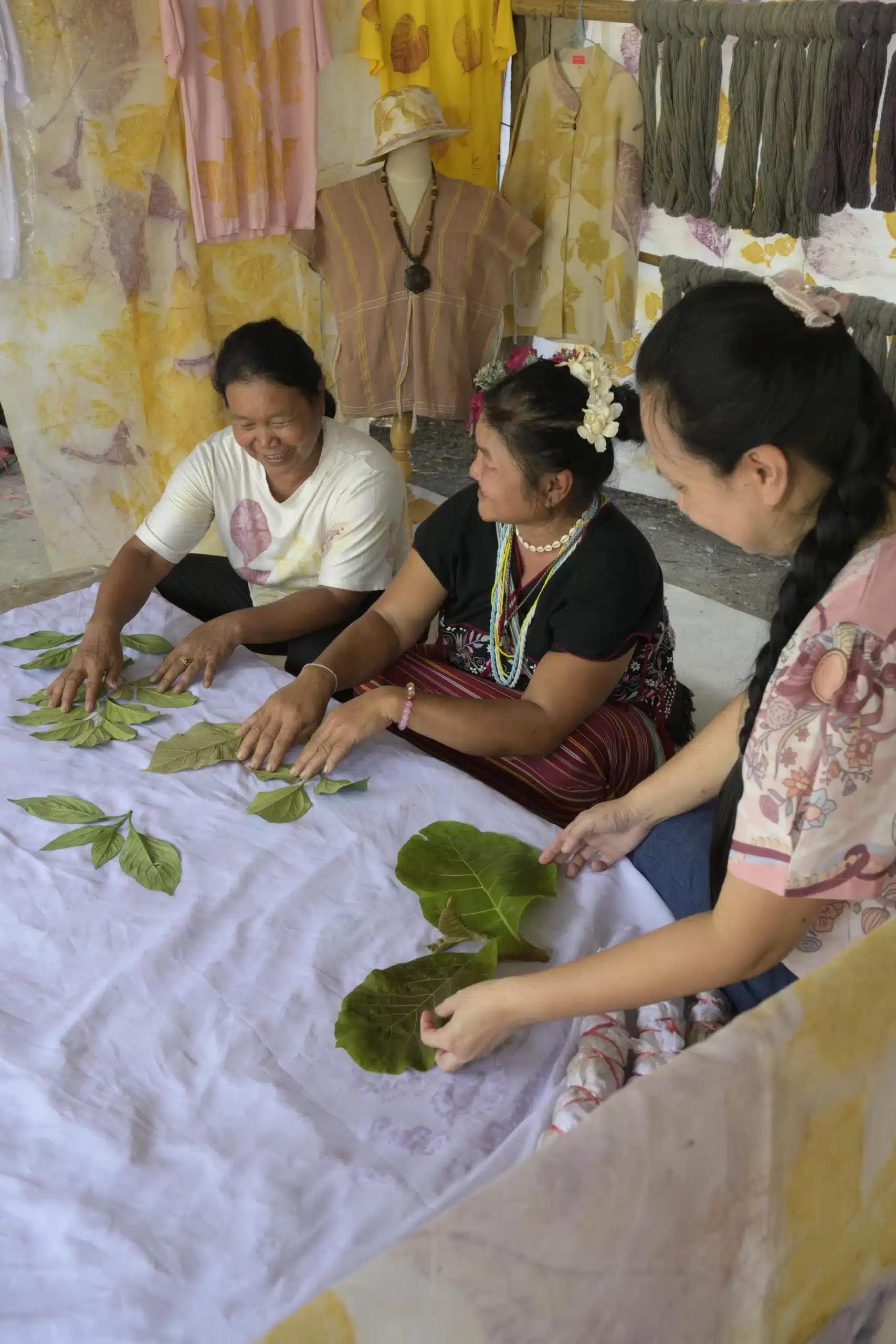 A group of women working with leaves on a table near a zipline in Chiang Mai.